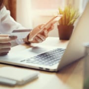 image of person holding phone and credit card with laptop in front of them