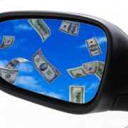 image of rearview mirror with money floating