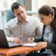 couple with laptop reviewing notebook