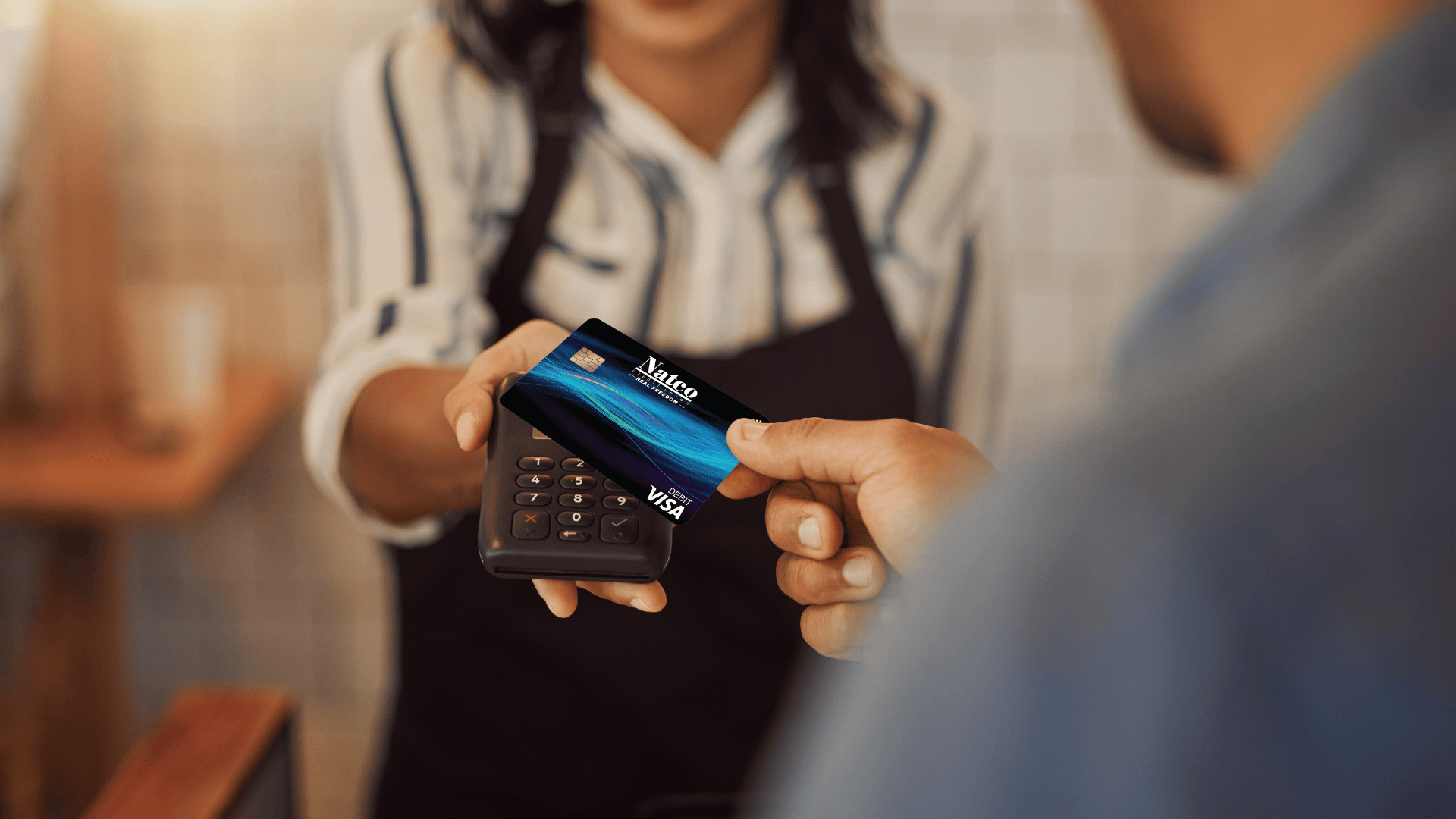 close up of person using natco debit card tap to pay