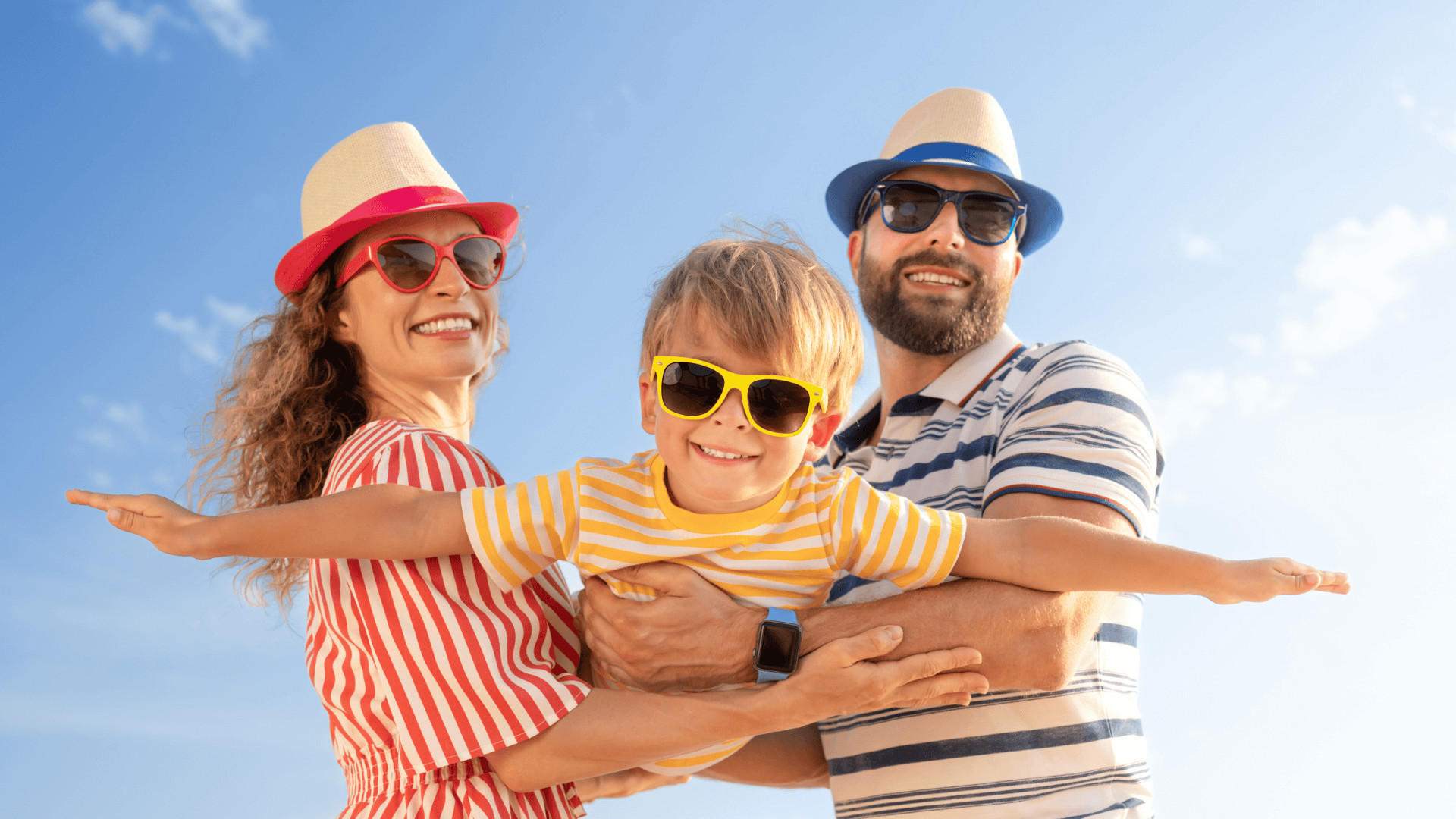man and woman holding small child on vacation wearing sunglasses